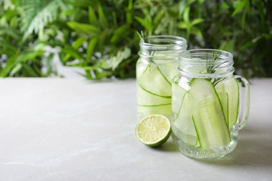 Photo of Mason jars of fresh cucumber water on table. Space for text