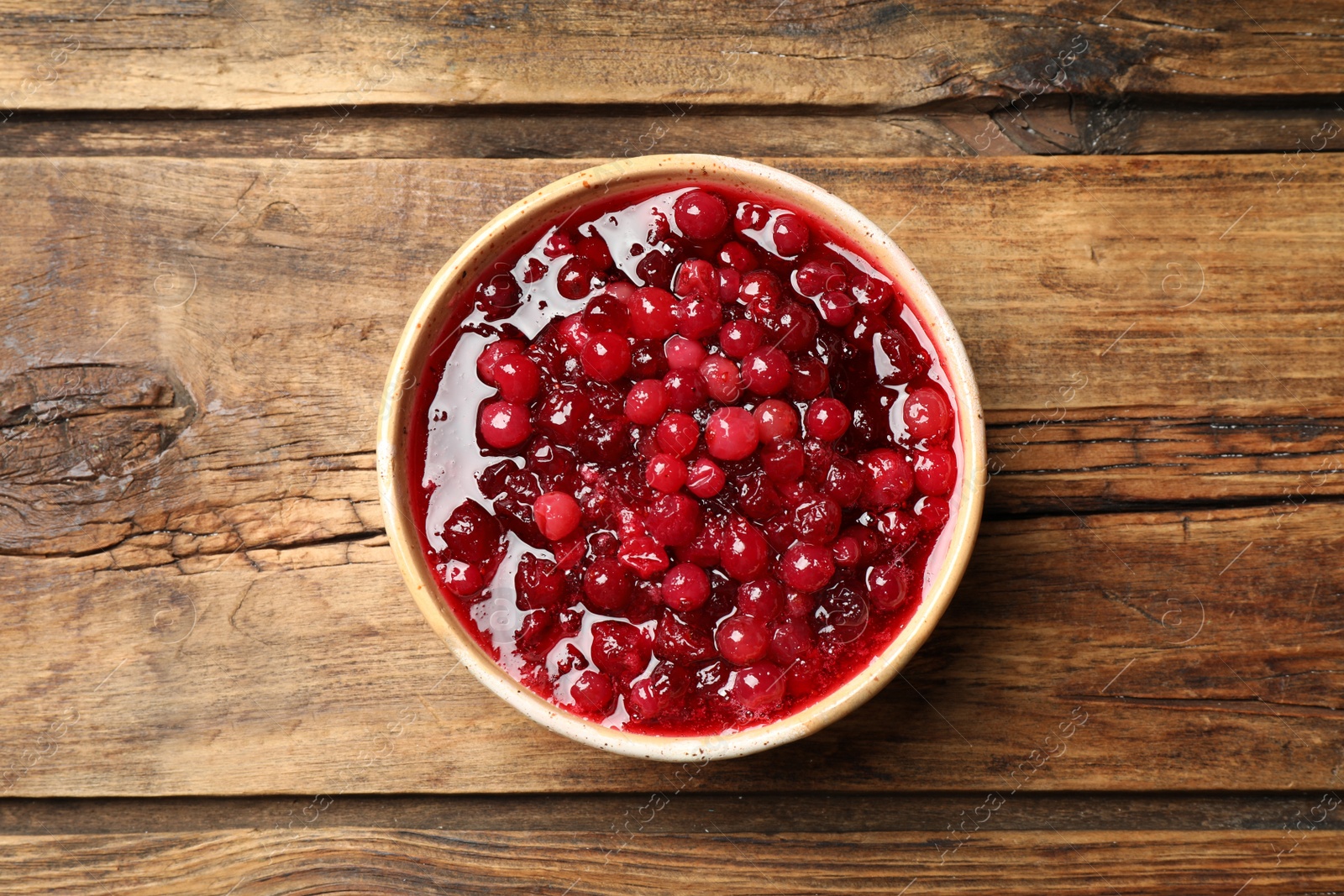 Photo of Fresh cranberry sauce on wooden table, top view