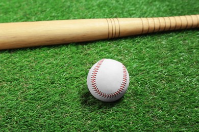 Photo of Wooden baseball bat and ball on green grass. Sports equipment