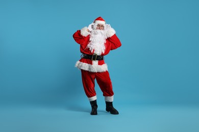 Photo of Merry Christmas. Santa Claus in headphones listening to music on light blue background