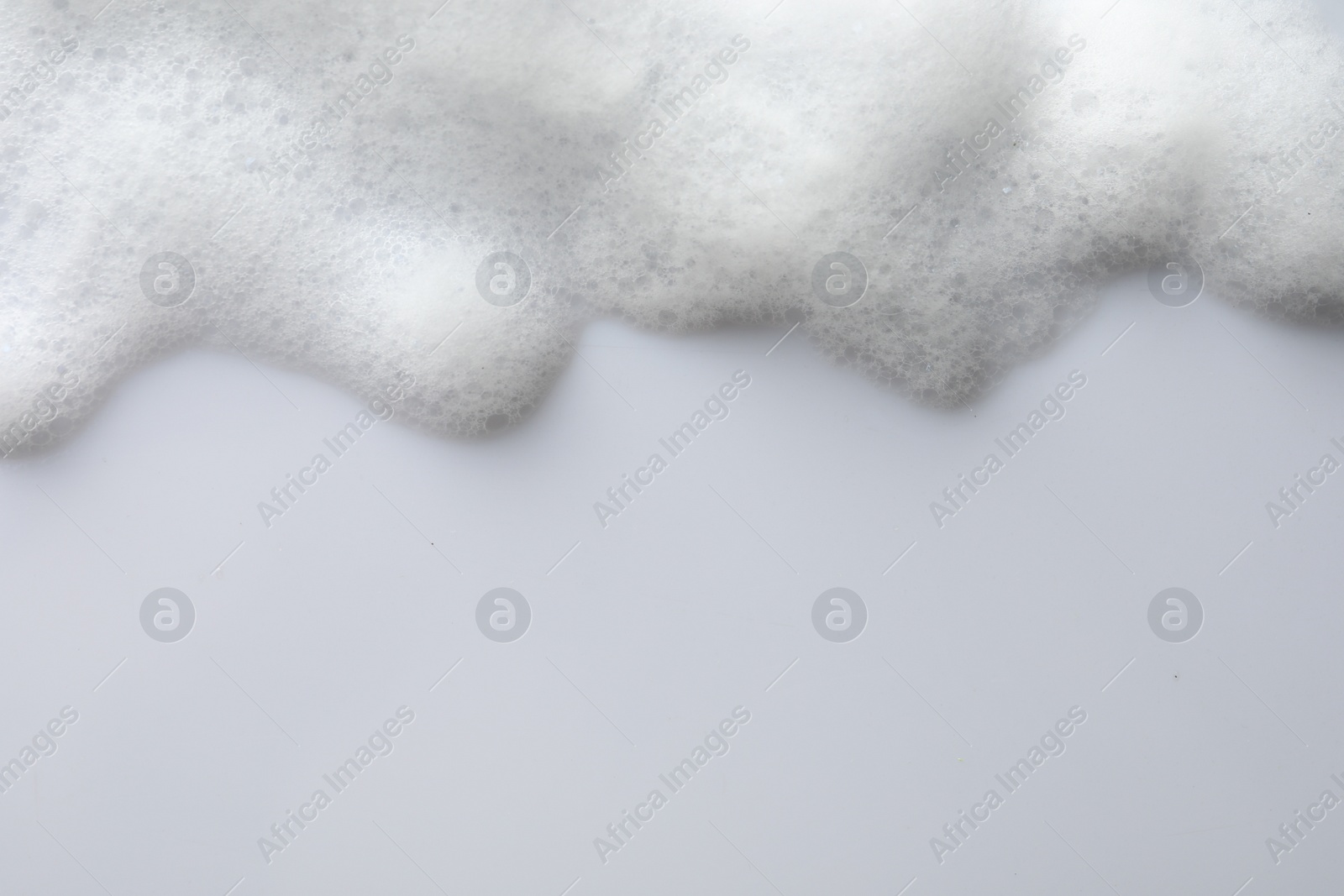 Photo of Fluffy soap foam on white background, top view