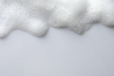 Fluffy soap foam on white background, top view