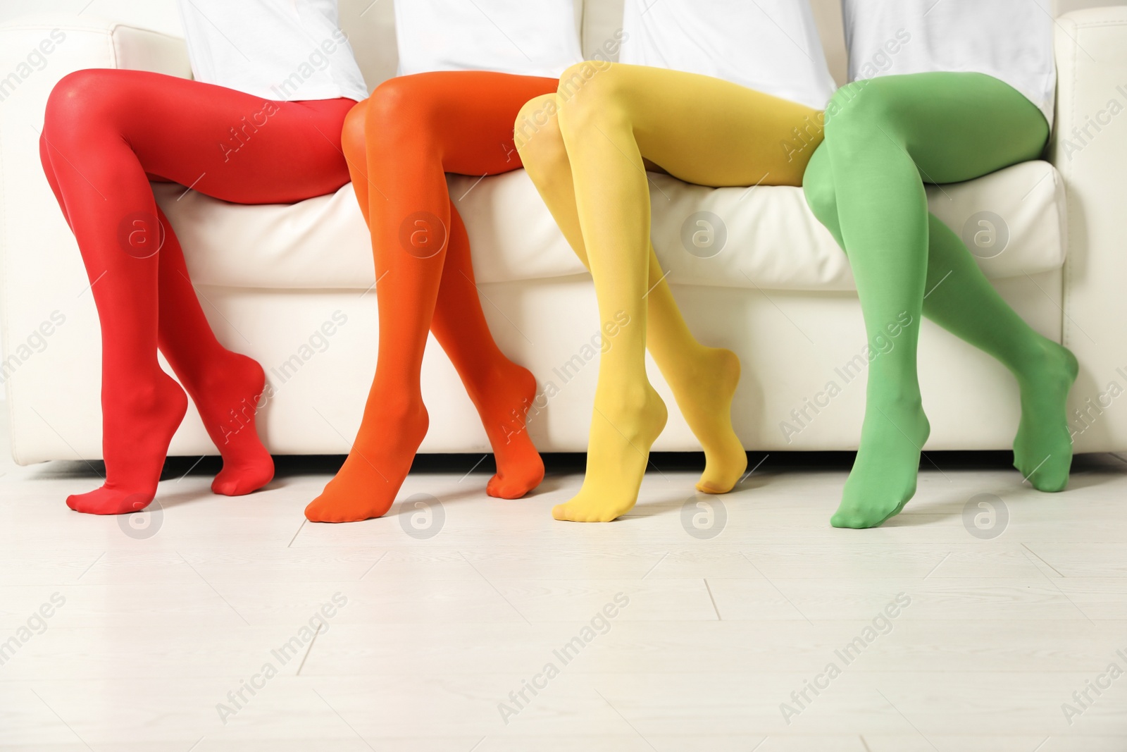 Photo of Women wearing colorful tights sitting on sofa indoors, closeup