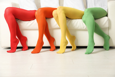 Women wearing colorful tights sitting on sofa indoors, closeup