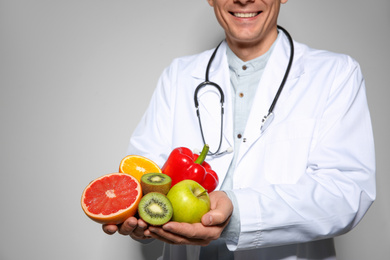 Nutritionist with fresh products on light grey background, closeup