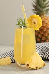 Photo of Tasty pineapple cocktail with rosemary and sliced fruit on light grey marble table
