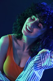 Photo of Beautiful young woman posing on color background in neon lights