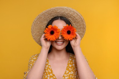 Woman covering her eyes with spring flowers on yellow background