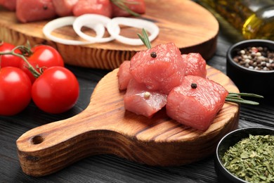 Raw beef meat and different ingredients for cooking delicious goulash on black wooden table, closeup