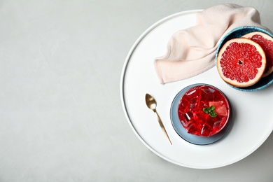 Photo of Flat lay composition with grapefruit jelly in bowl on light table. Space for text