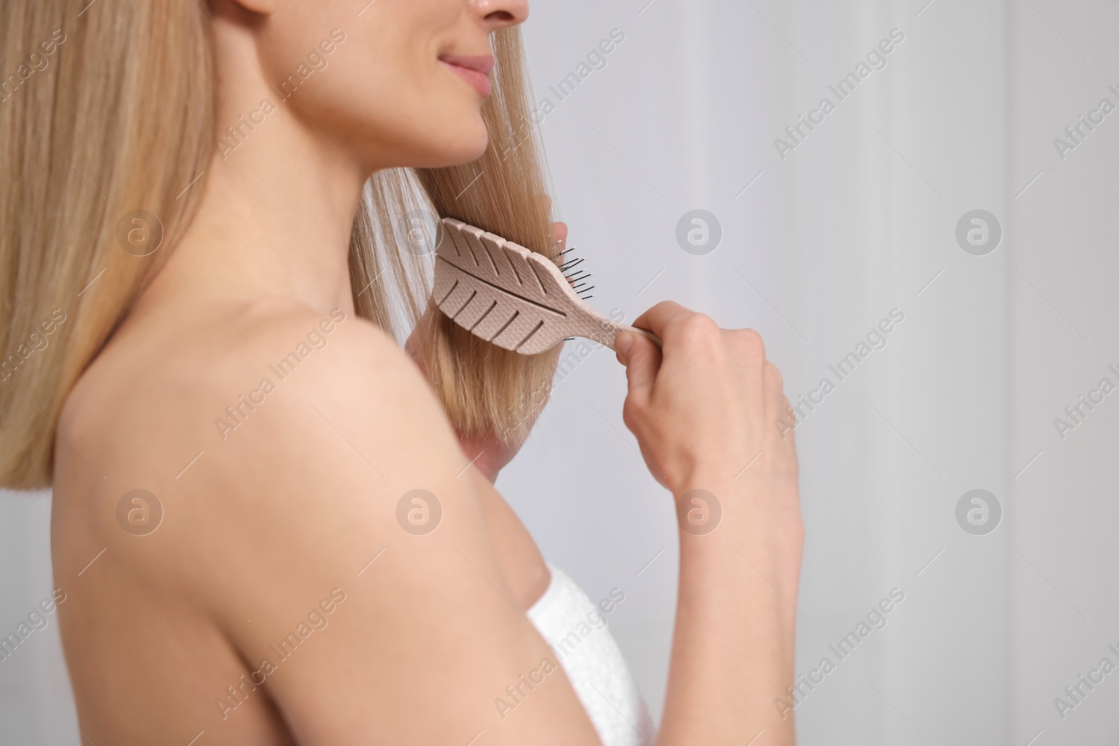 Photo of Woman brushing her hair indoors, closeup view