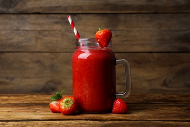 Mason jar with delicious strawberry smoothie and fresh berries on wooden table