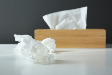 Photo of Used paper tissues and wooden holder on white table
