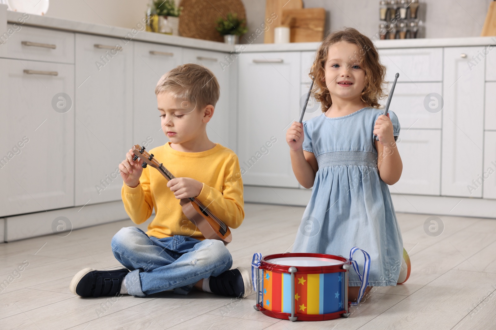 Photo of Little children playing toy musical instruments in kitchen