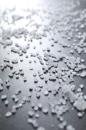 Photo of Scattered white natural salt on black table, closeup