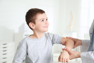 Professional orthopedist examining little patient's arm  in clinic