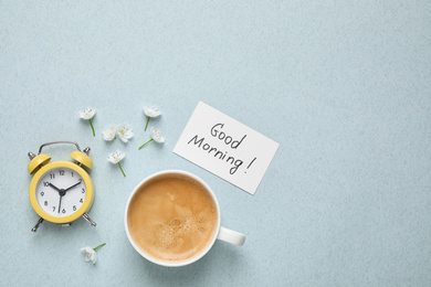 Flat lay composition with message GOOD MORNING and coffee on light blue background. Space for text