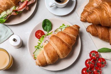 Flat lay composition with tasty croissant sandwich on light grey marble table