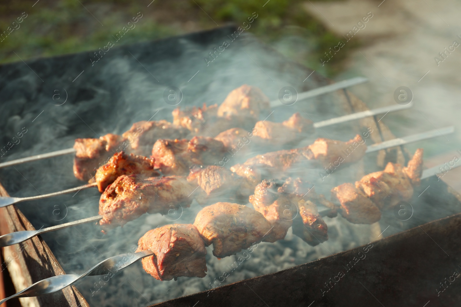 Photo of Cooking delicious meat on metal brazier outdoors