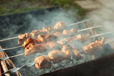 Photo of Cooking delicious meat on metal brazier outdoors