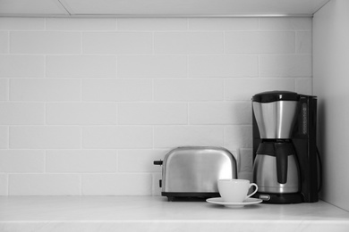 Photo of Modern toaster and coffeemaker on countertop in kitchen. Space for text