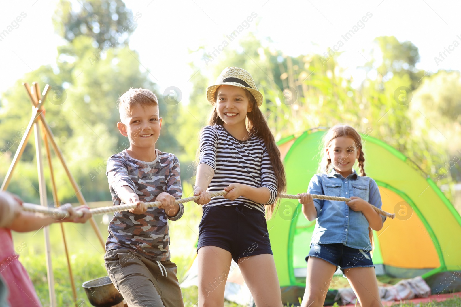 Photo of Little children pulling rope outdoors. Summer camp