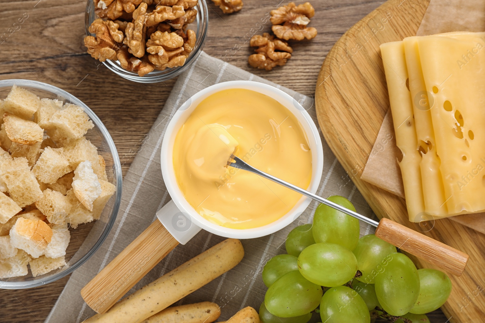 Photo of Flat lay composition with pot of tasty cheese fondue on wooden table