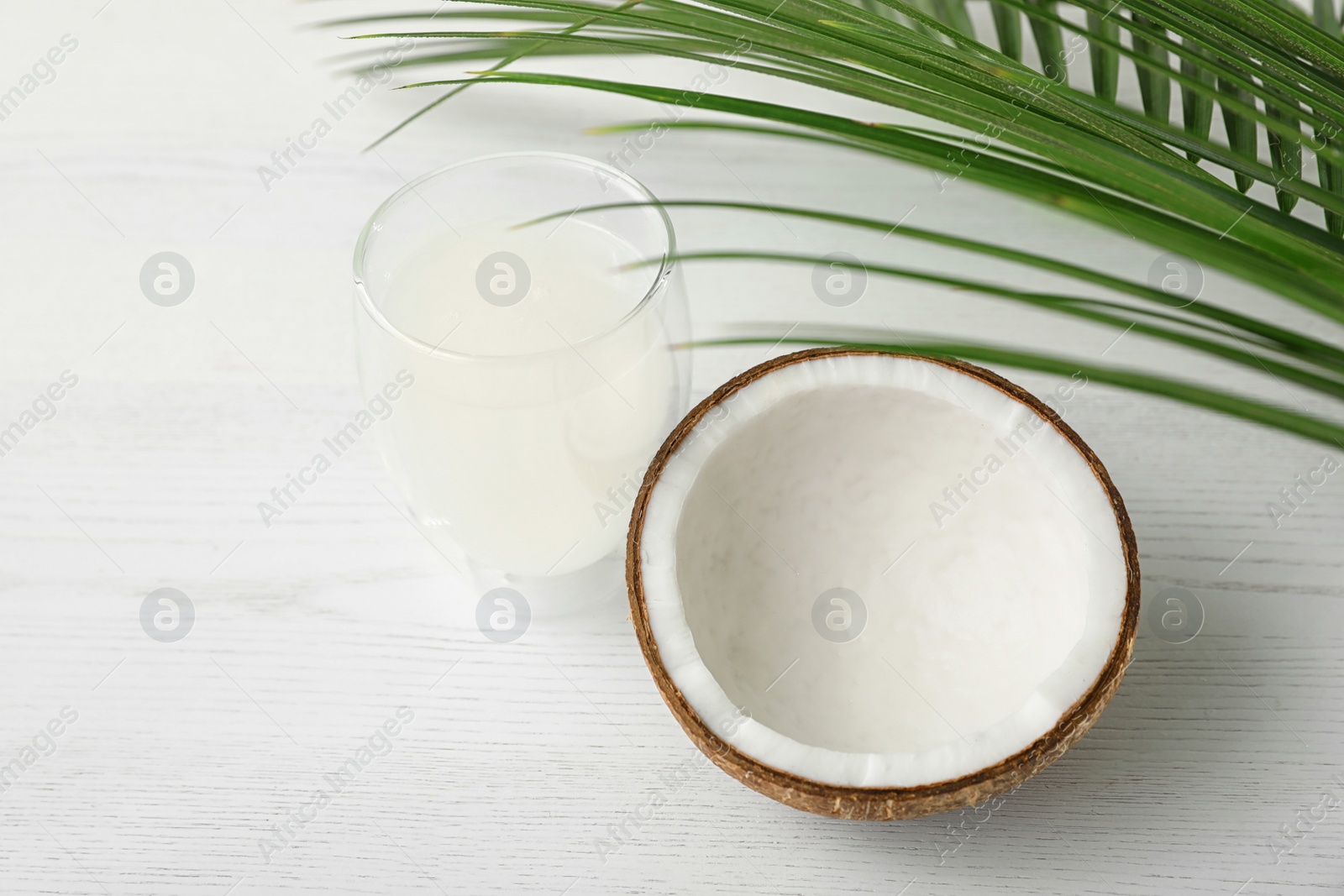 Photo of Composition with glass of coconut water on white wooden background