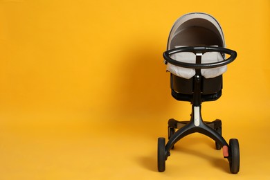Photo of Baby carriage. Modern pram on yellow background, space for text