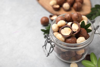 Tasty Macadamia nuts in jar on light grey table, closeup. Space for text