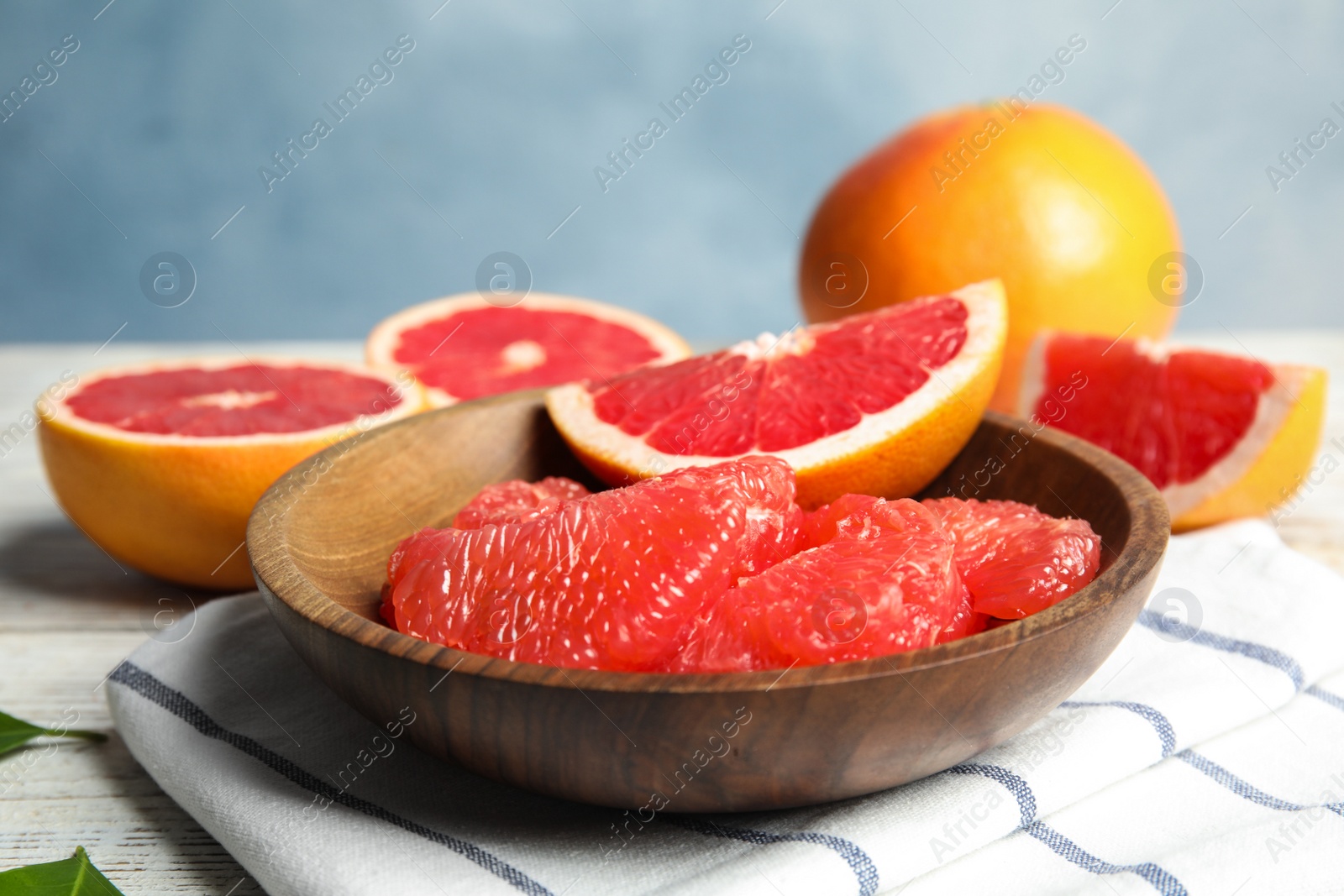 Photo of Composition with plate of grapefruits on table against color background