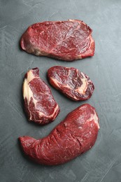 Photo of Pieces of raw beef meat on grey table, flat lay