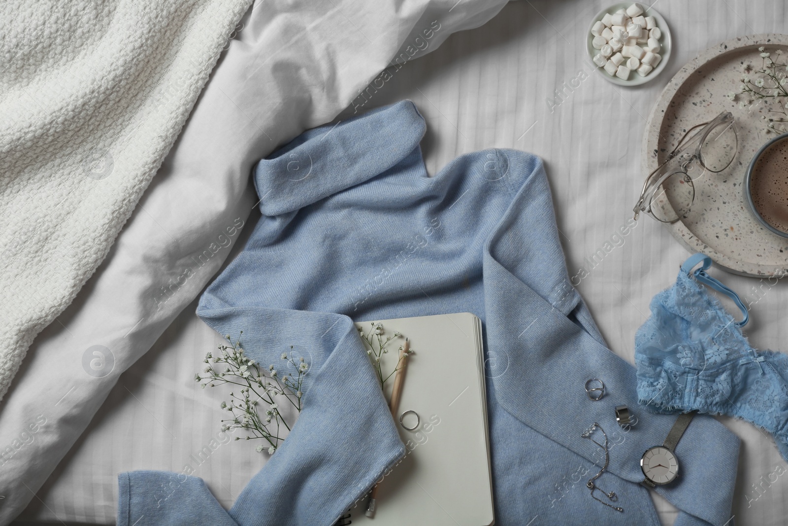 Photo of Stylish look with cashmere sweater, flat lay. Women's clothes and accessories on bed