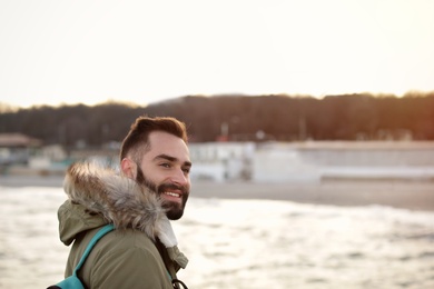 Photo of Stylish young man with backpack near sea