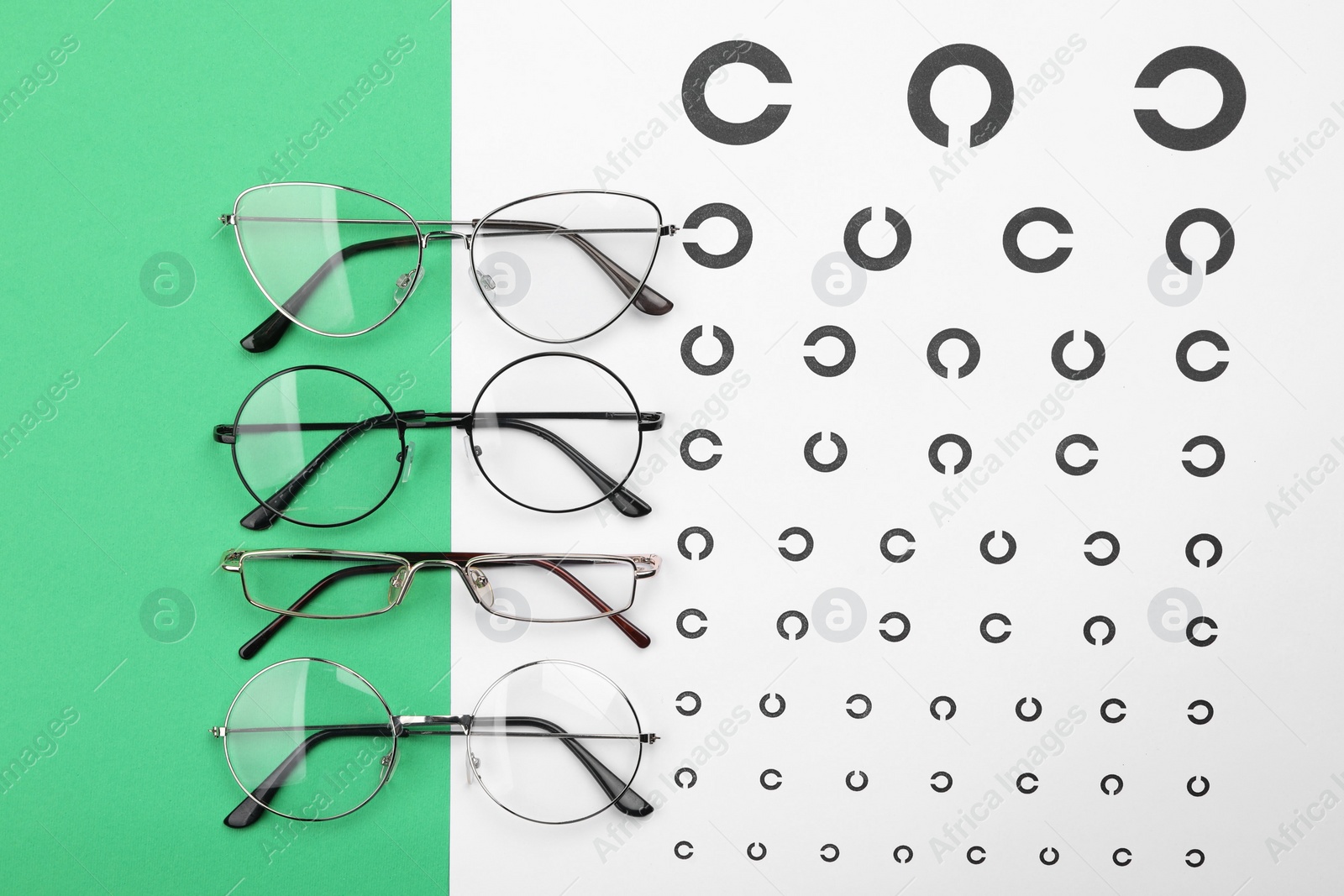 Photo of Vision test chart and glasses on green background, flat lay