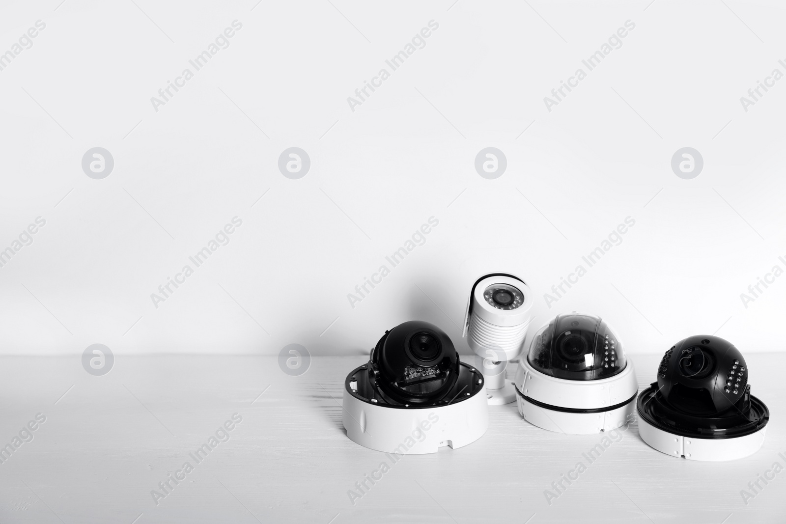 Photo of Modern CCTV cameras on table against light background. Home alarm system