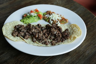 Plate with delicious tacos served on wooden table