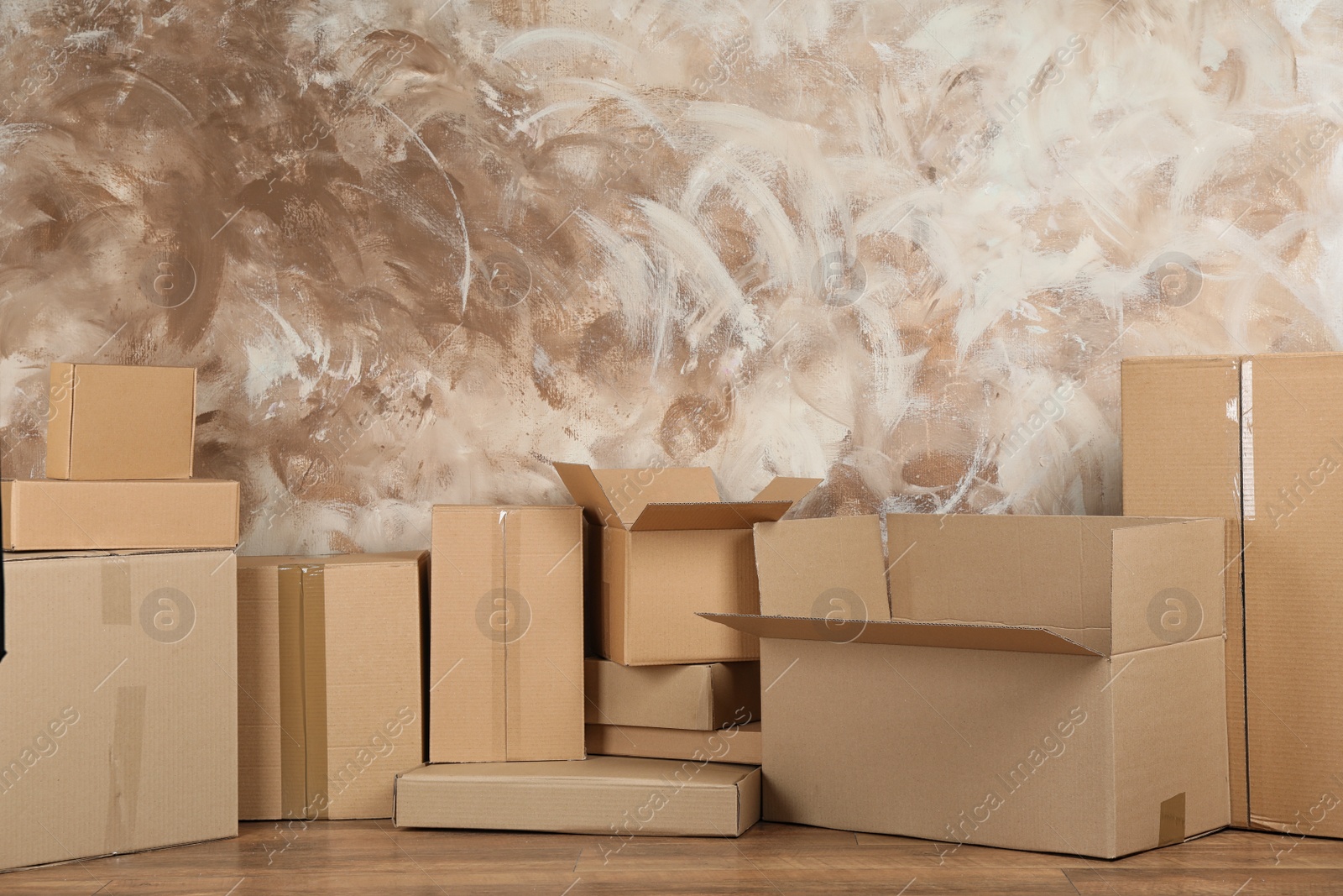 Photo of Pile of cardboard boxes near brown wall indoors