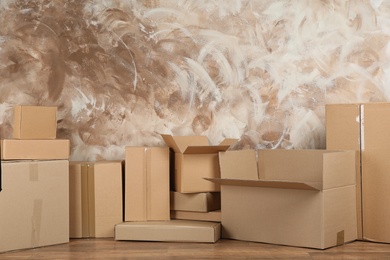 Pile of cardboard boxes near brown wall indoors