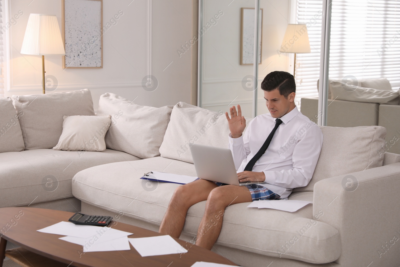 Photo of Man in shirt and underwear working on laptop indoors. Stay at home concept