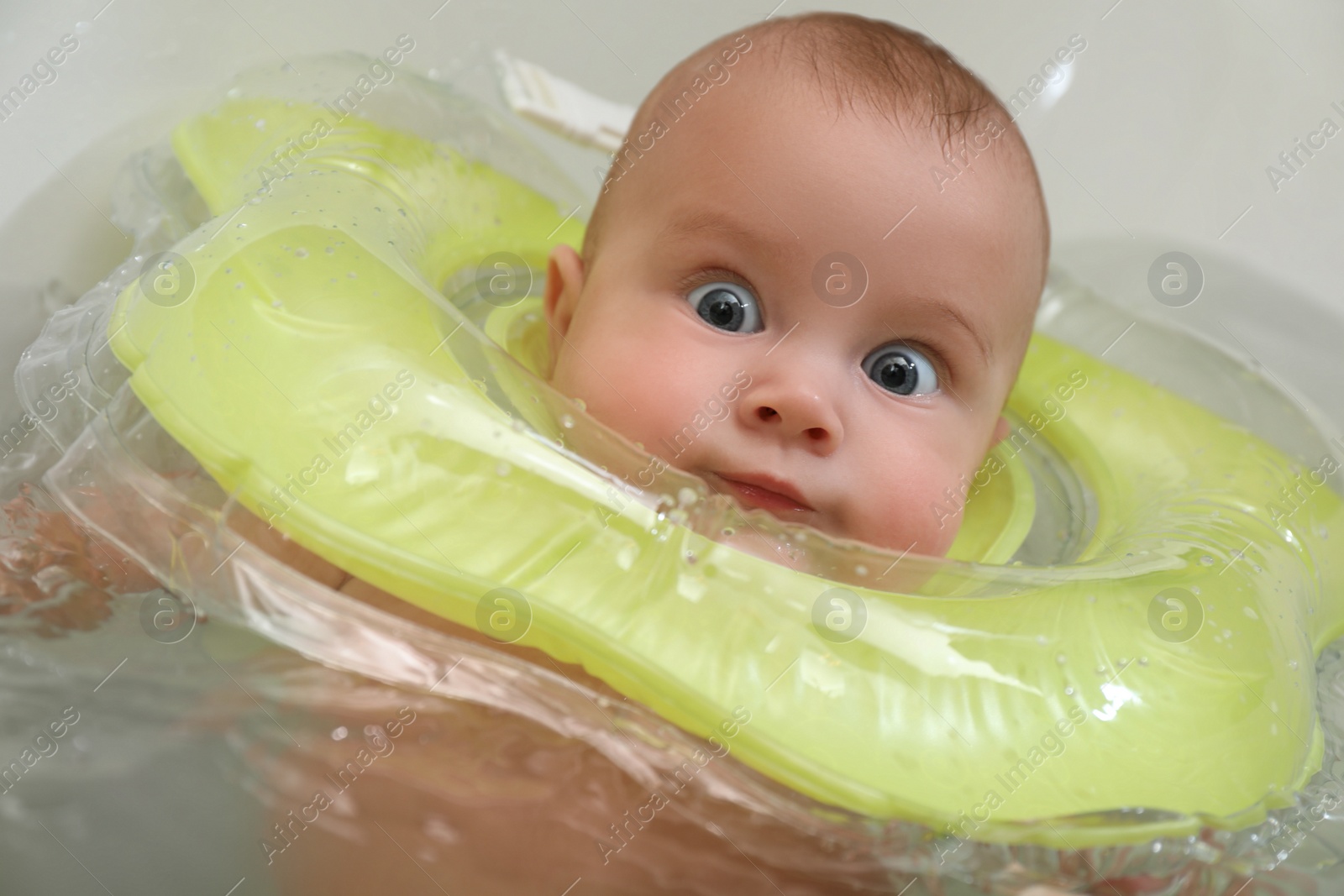 Photo of Cute little baby swimming with inflatable ring in bath