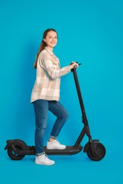 Happy woman with modern electric kick scooter on light blue background