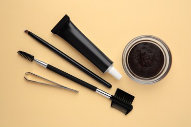 Photo of Flat lay composition with eyebrow henna and tools on beige background
