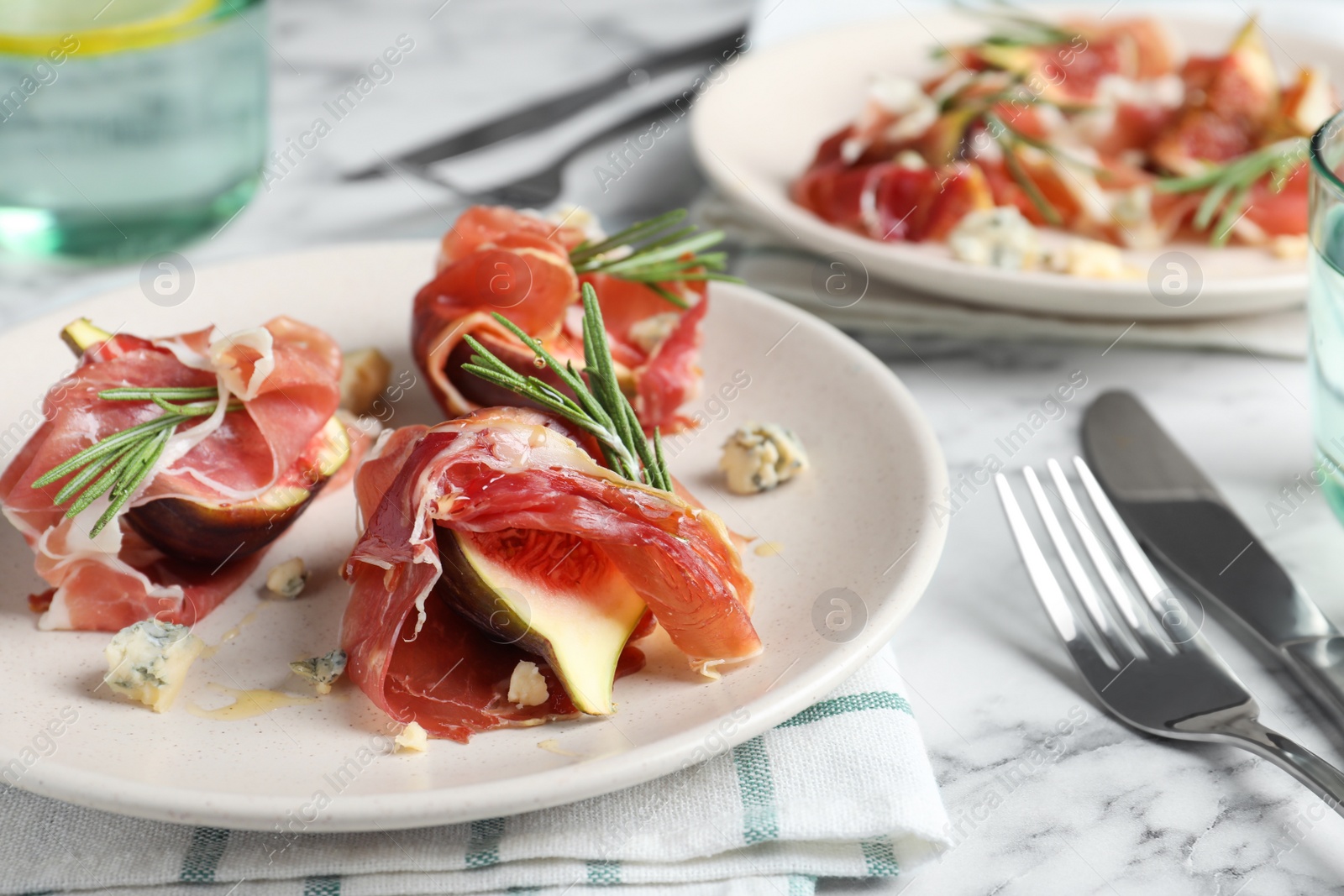 Photo of Delicious ripe figs and prosciutto served on white marble table, closeup