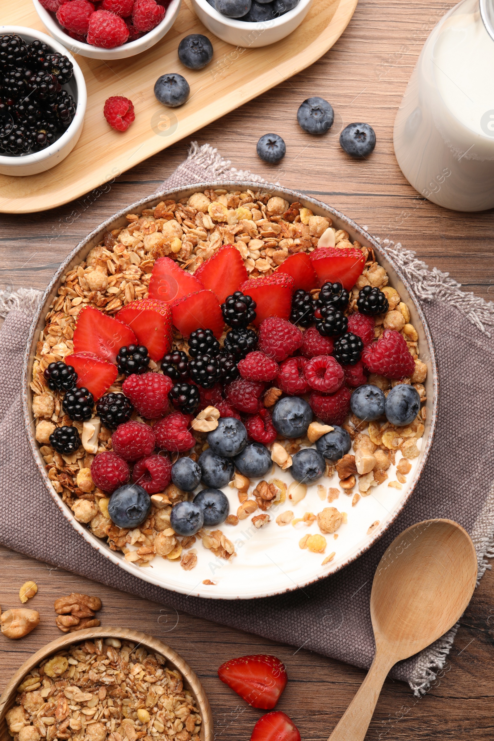 Photo of Healthy muesli served with berries on wooden table, flat lay