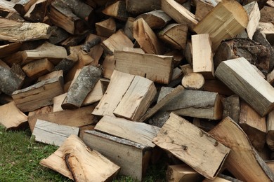 Photo of Pile of chopped firewood on grass outdoors