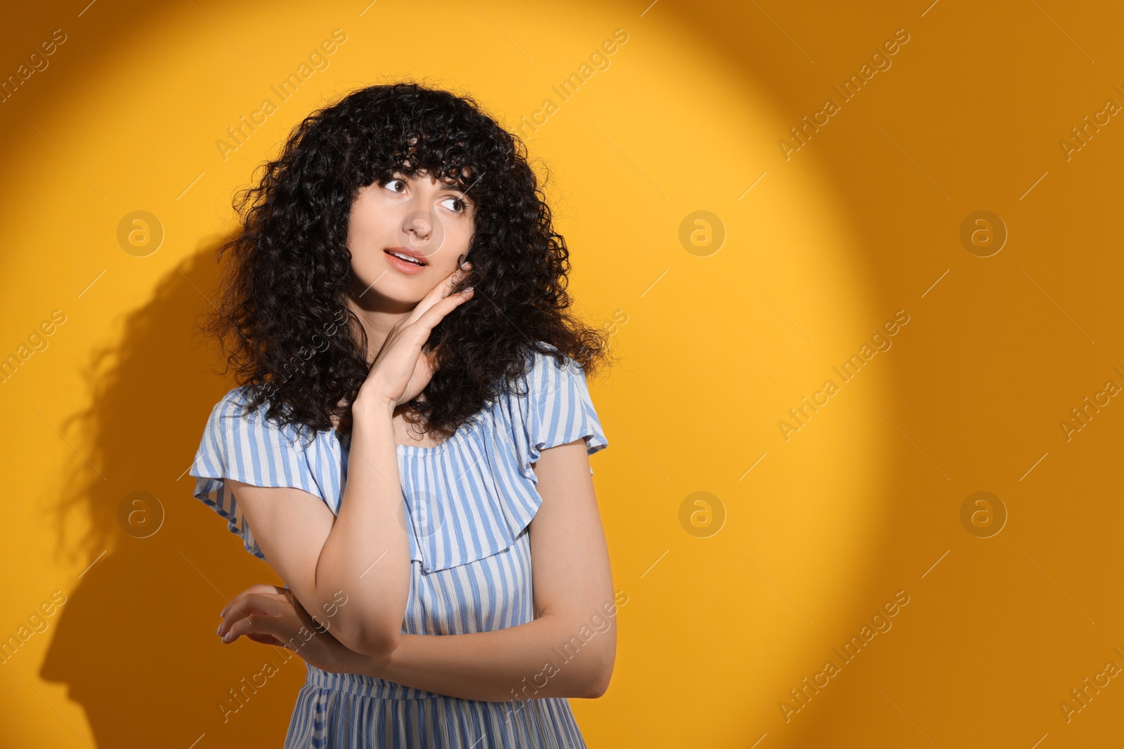 Photo of Beautiful young woman in sunlight on orange background, space for text