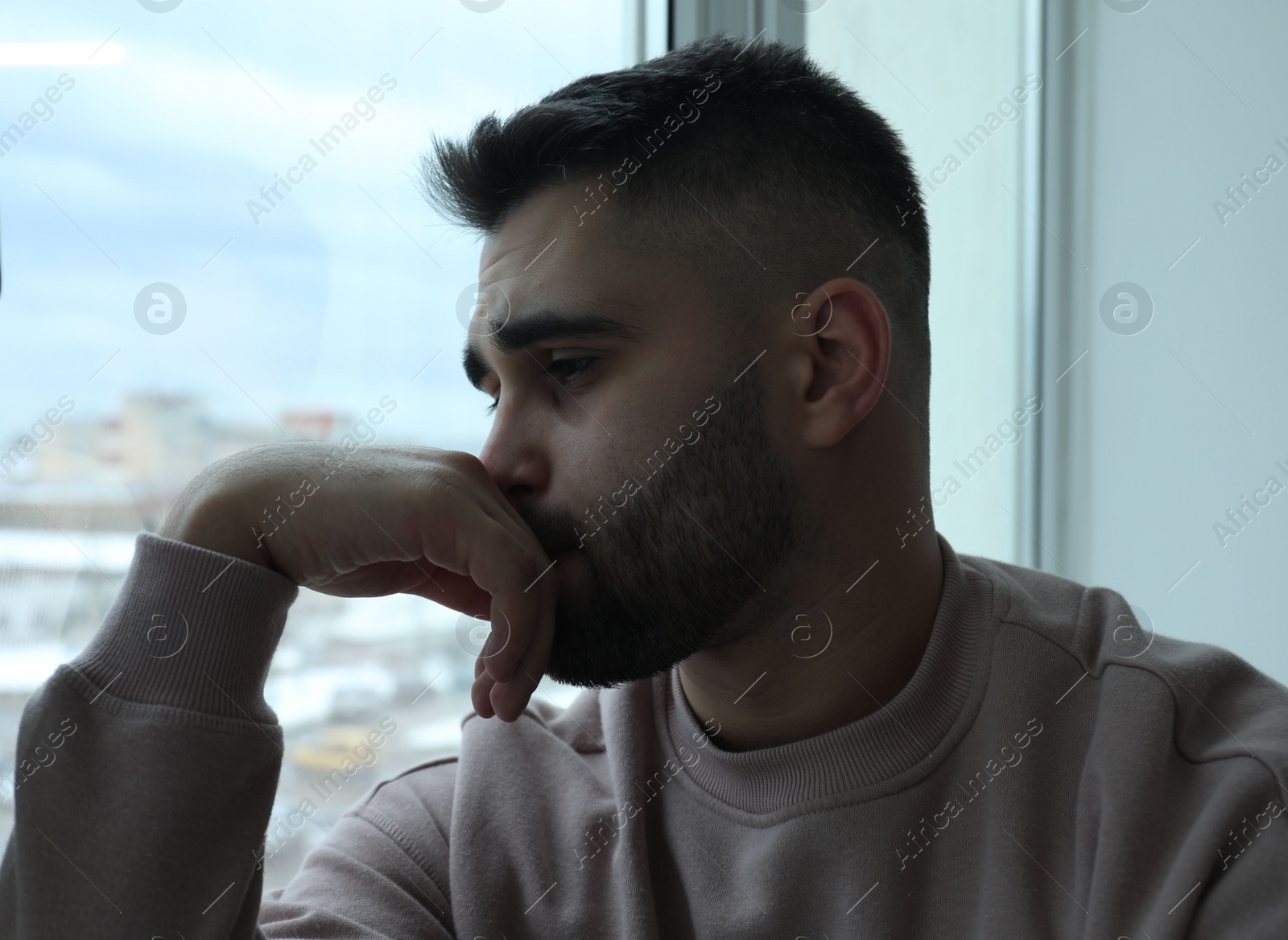 Photo of Portrait of sad man near window at home