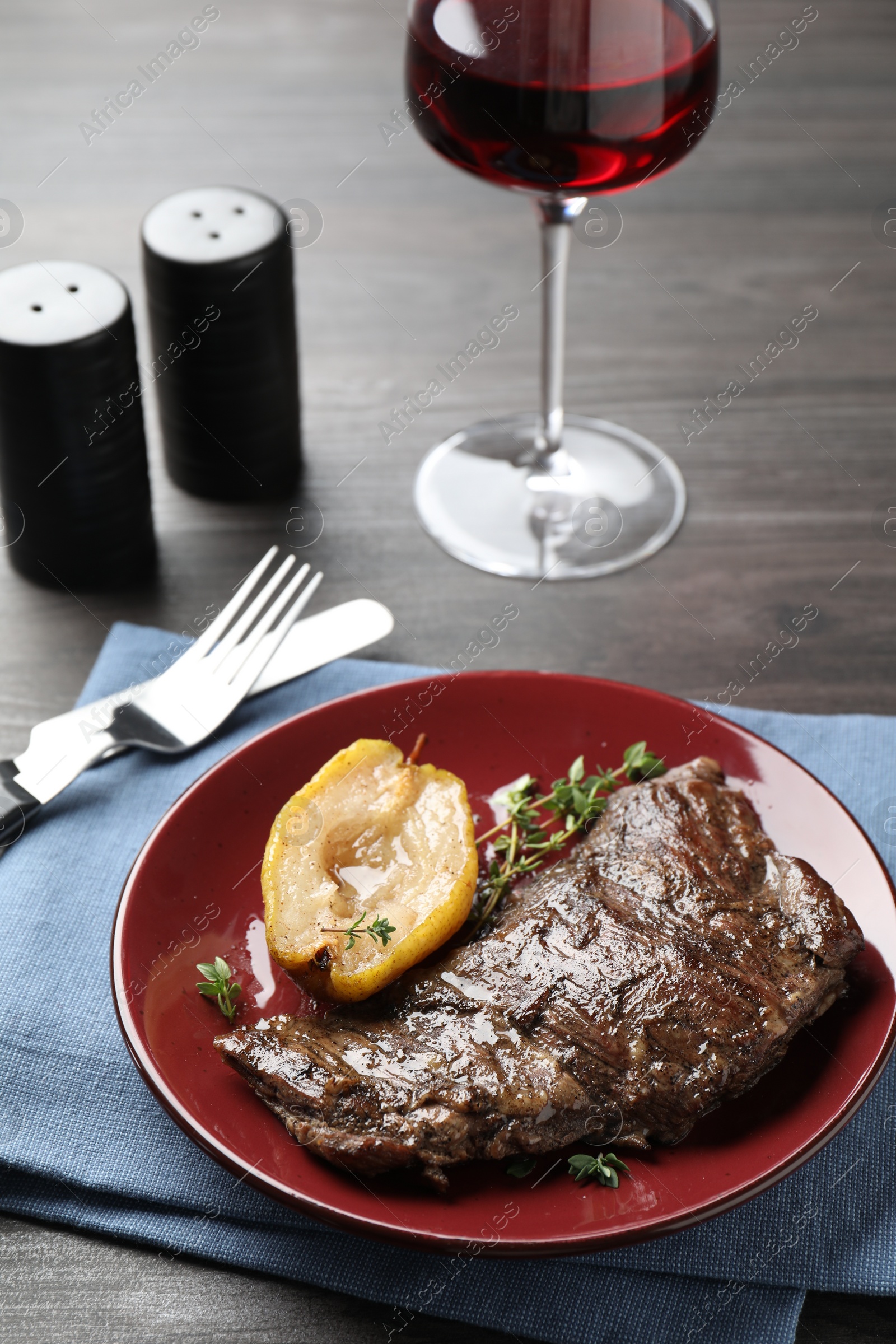 Photo of Delicious roasted beef meat and caramelized pear served on grey wooden table