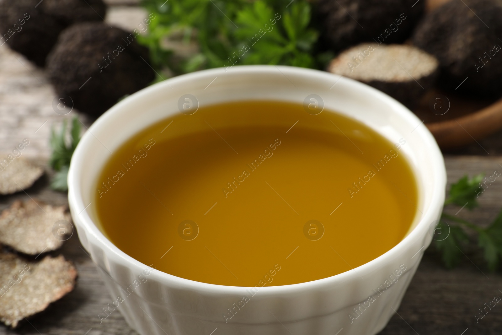 Photo of Fresh truffle oil in bowl on table, closeup